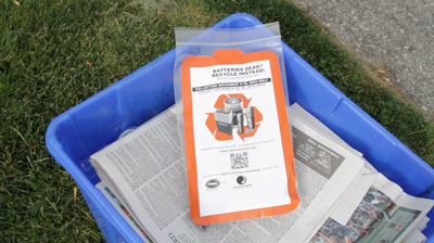 Battery recycling bag sits on top of a blue box during fall curbside collections